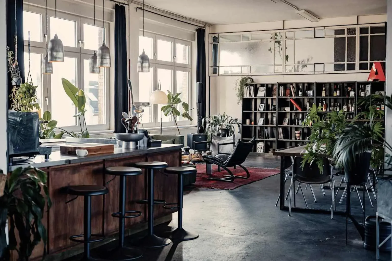 Offener Loft-Bereich im 310 m² Mietstudio Berlin mit moderner Küche, Barhockern und gemütlicher Lounge im Industrial-Style.